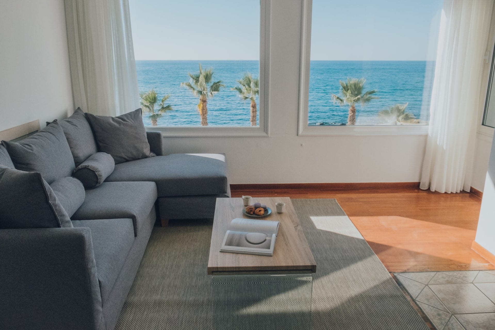 Living room sofa framed by windows looking onto the sea
